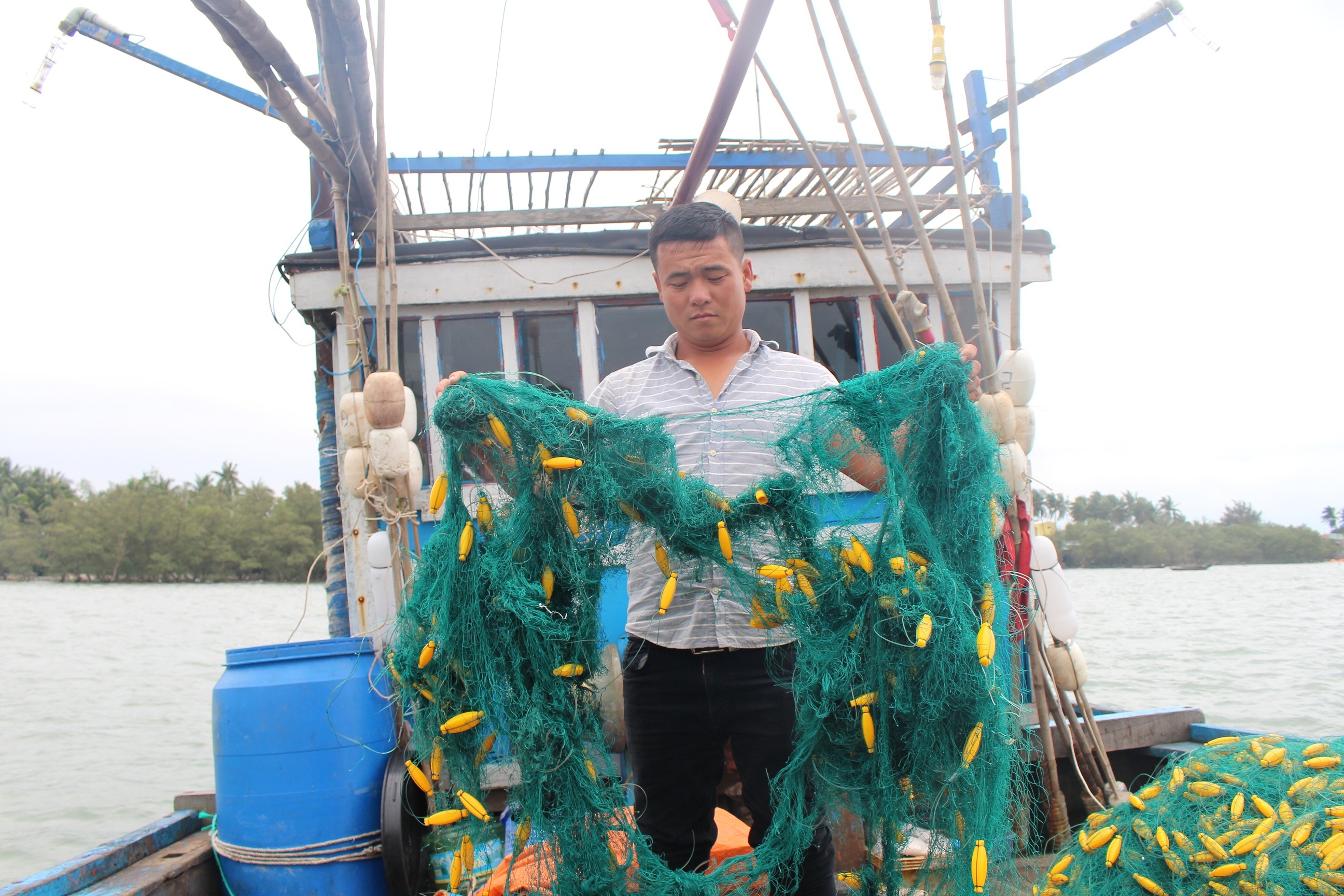 Ngư dân Nguyễn Tấn Sơn  chủ tàu QNa 90822 cầm tấm lưới bị tàu lạ cắt phá
